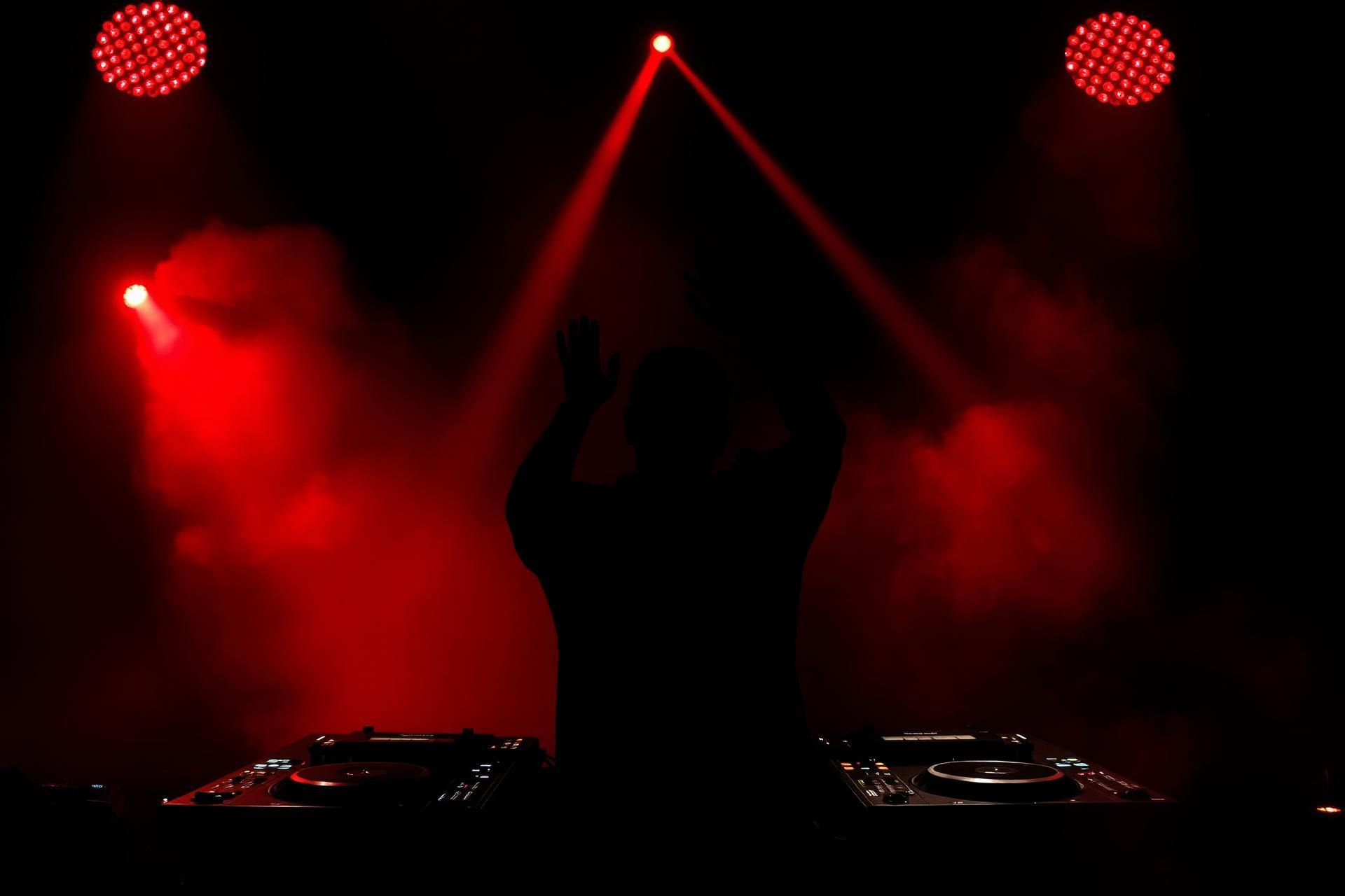 DJ performing under crimson stage lights